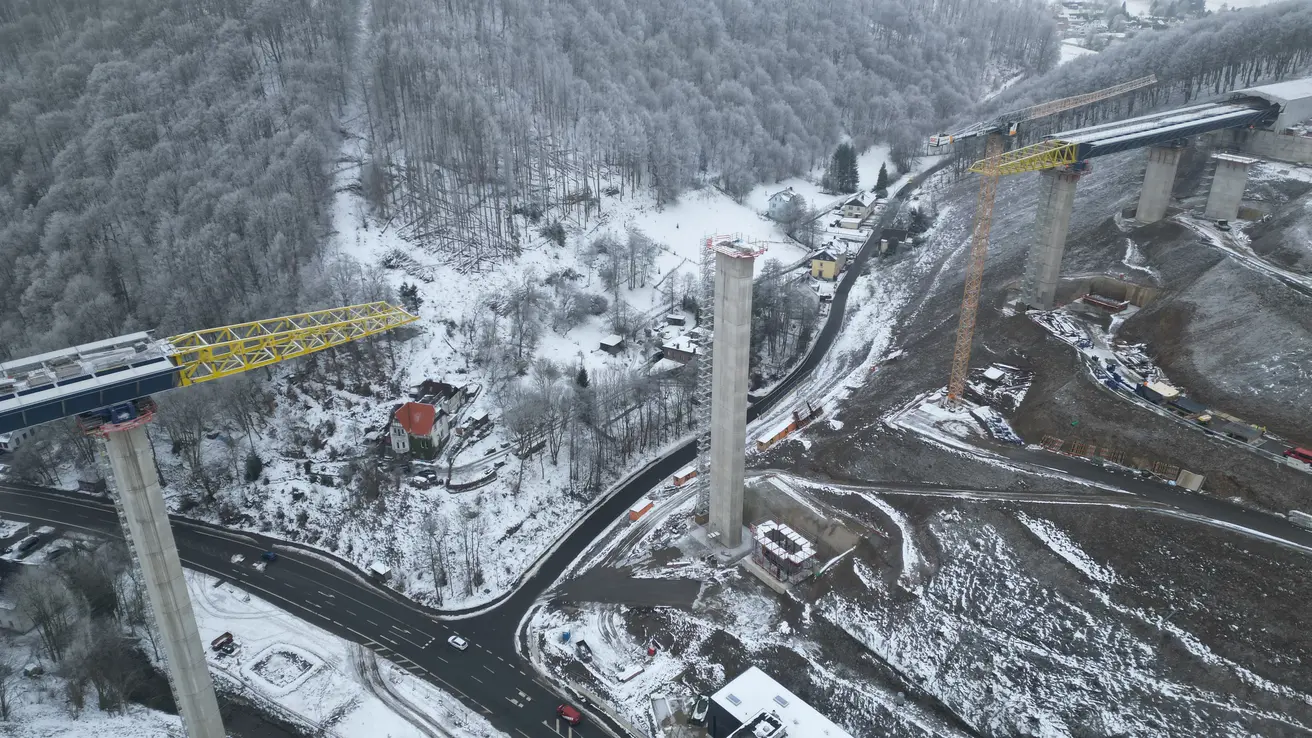 Blick aus der Luft auf das verschneite Rahmedetal samt Brückenbaustelle.