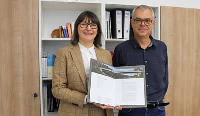 Magdalena Gabler, Abteilungsleiterin Konstruktiver Ingenieurbau und Lärmschutzbauwerke, und Markus Wagner, Geschäftsbereichsleiter Bau und Erhaltung, mit der Urkunde des Ingenieurpreises des Deutschen Stahlbaus 2024